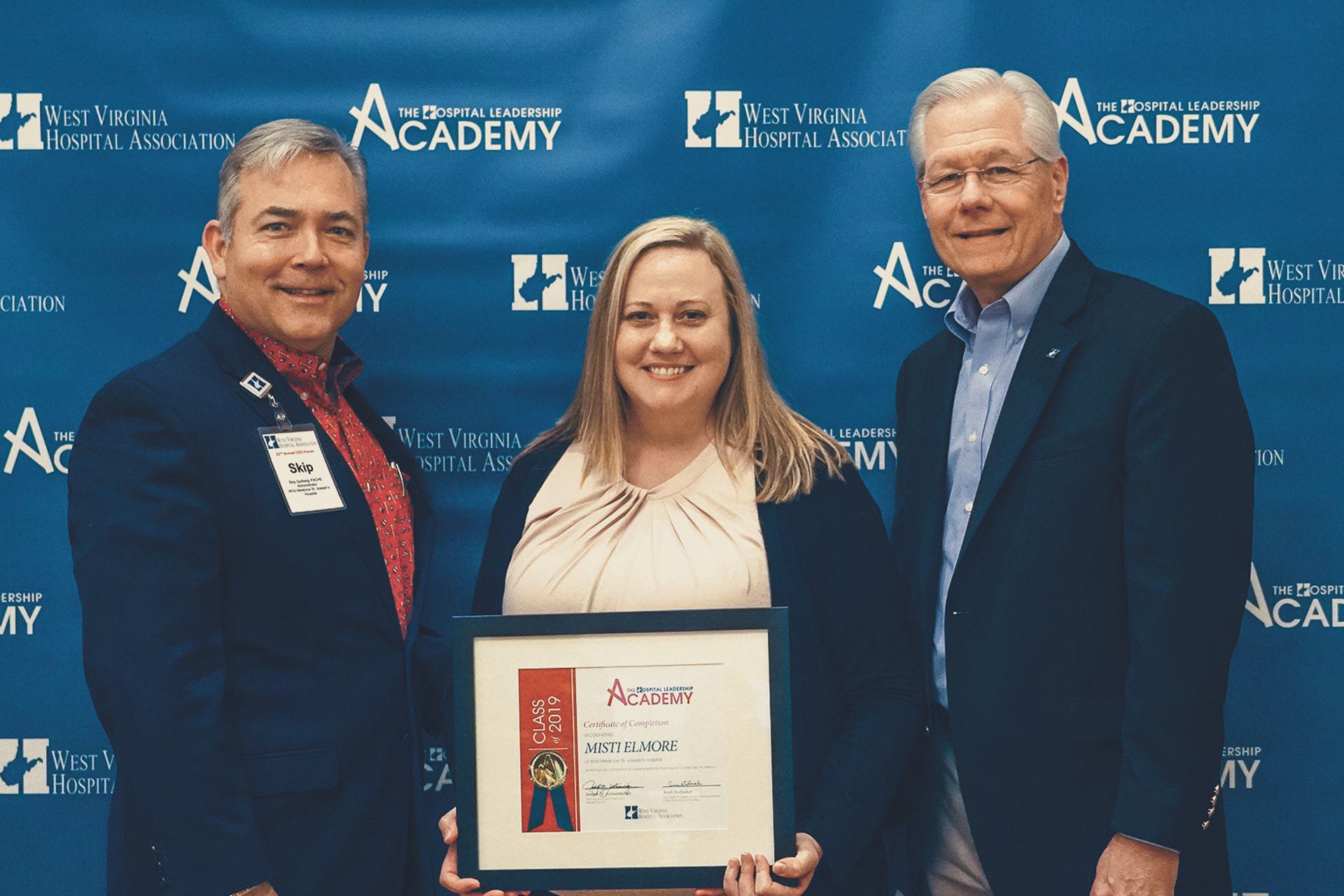 Skip Gjolberg, President of St. Joseph’s Hospital (left) and Joseph Letnaunchyn, President and CEO of the WVHA Association (right), present Misti Elmore with her Certification of Completion.