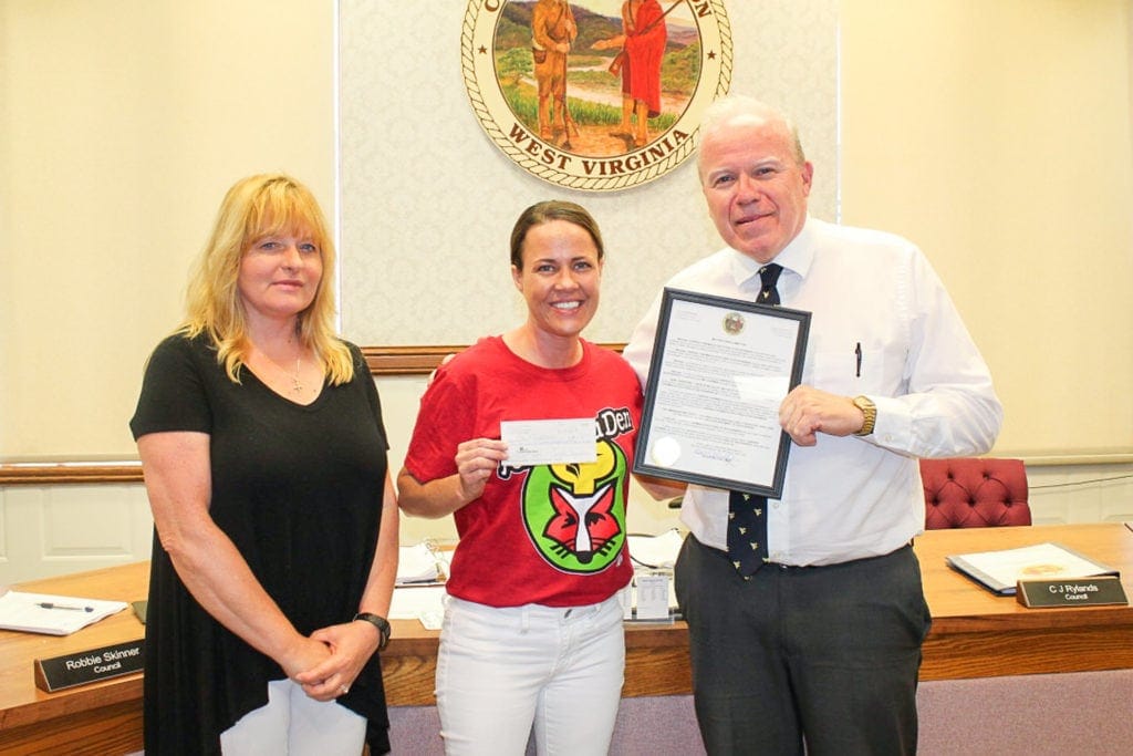 Buckhannon mayor David McCauley, right, and SYCC diretor Debora Brockleman, left, present Fox's Pizza owner Caressa Chapman with the city's Ambassador Award for her $1,700 donation to the new gym facility.