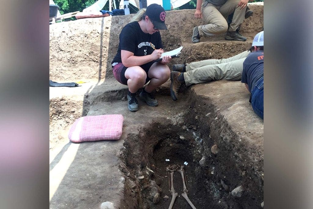 Assistant Professor Kristy Henson takes notes at the cemetary as they work on a gravesite.