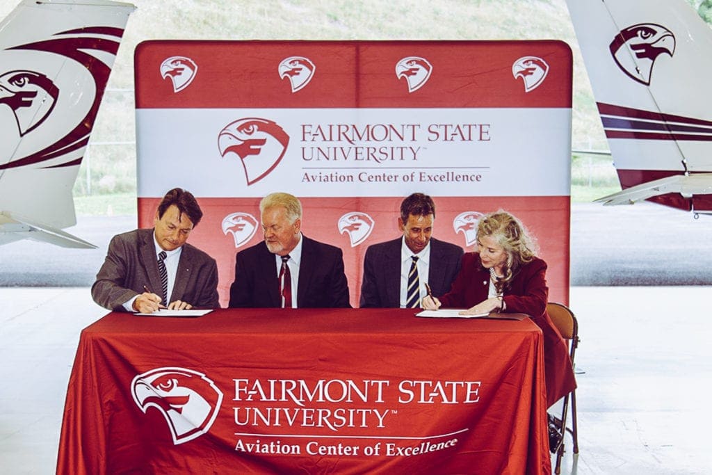 Commissioners Ernie VanGilder, Randy Elliott, and Rick Carcia sign the Memorandum of Understanding along with President Dr. Mirta Martin at the hangar Wednesday afternoon.