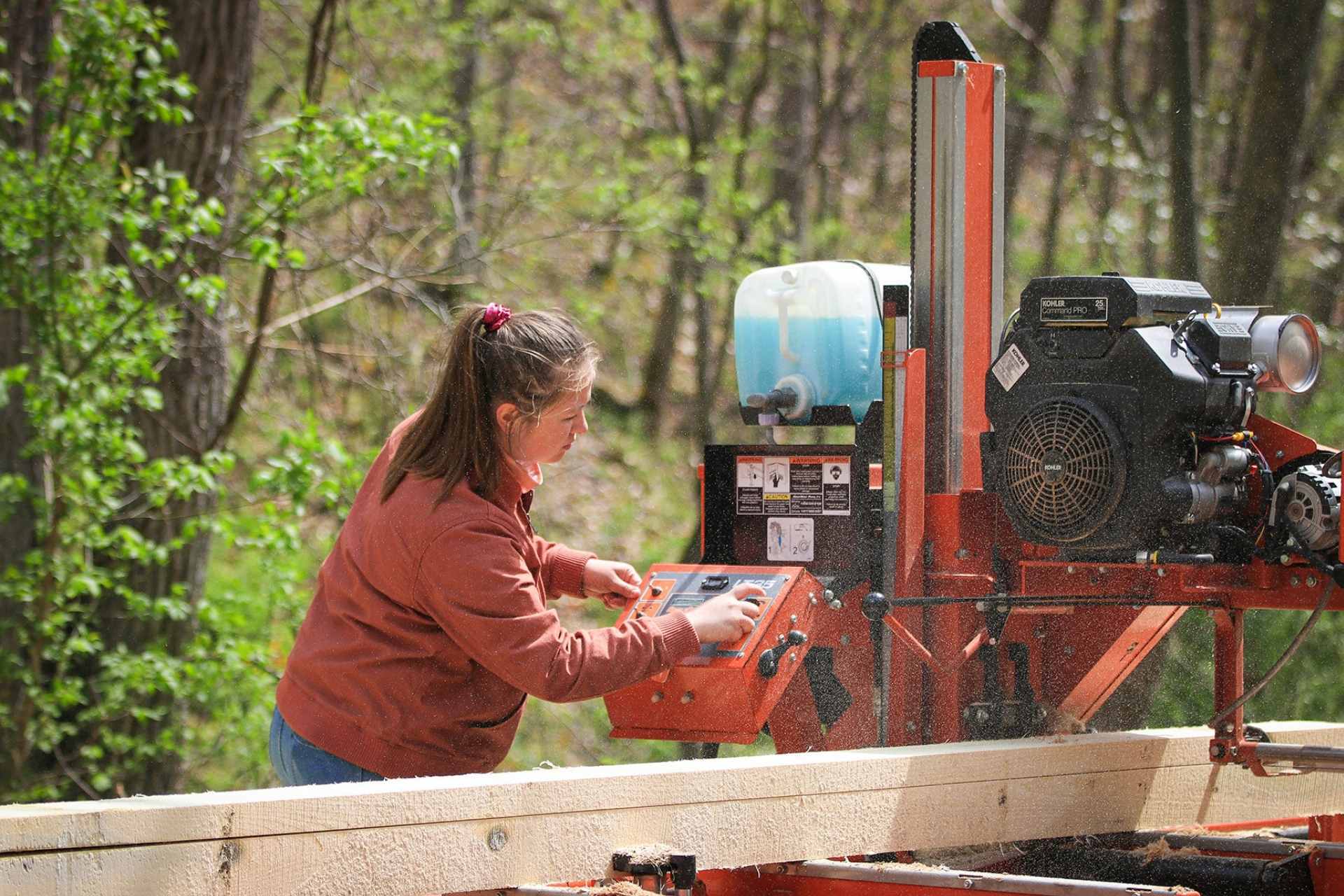 Glenville State College student Gabrielle Dean cuts a log down into boards using the College’s portable Wood-Mizer bandsaw.
