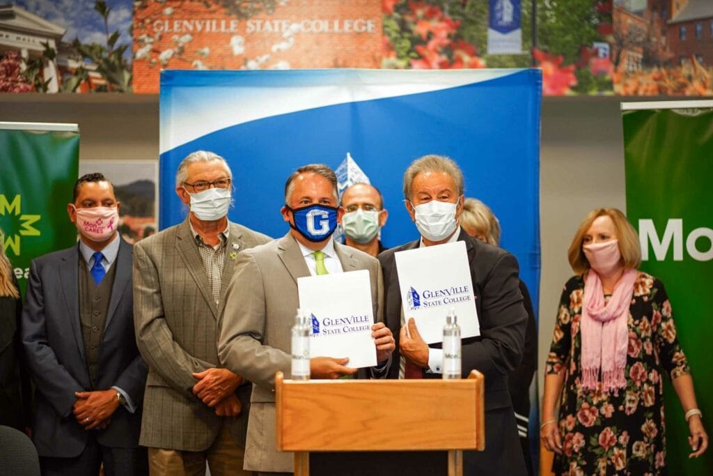 Mon Health System President and CEO, David Goldberg (left) and Glenville State College President, Dr. Mark A. Manchin are backed by members of the Glenville State Board of Governors and administration at a signing ceremony on October 20, 2021. The two signed an agreement inducting Glenville State College into the Mon Health Scholars program.