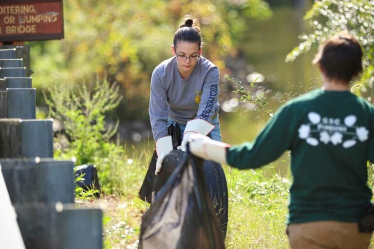 Glenville State College Natural Resource Management students Katlyne Rollyson (center, with tire) and Lexi Pletcher clear trash from around Stonewall Jackson Lake during a recent volunteer clean-up event.