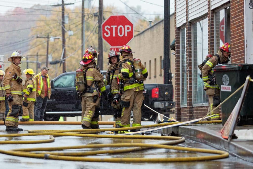 Firefighters gather on Spring Street Tuesday morning after extinguishing a small fire that occurred in the building that had burned previously in early October.