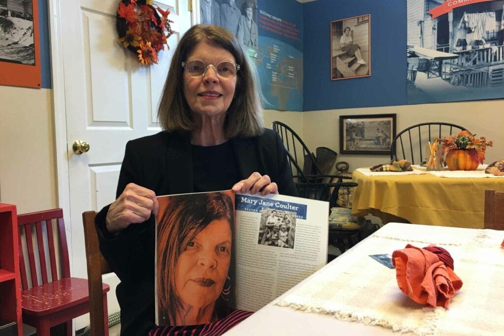 Mary Jane Coulter, who runs to Scotts Run Museum in Osage, holds up a book that she helped write about the area. Photo by Emily Allen.