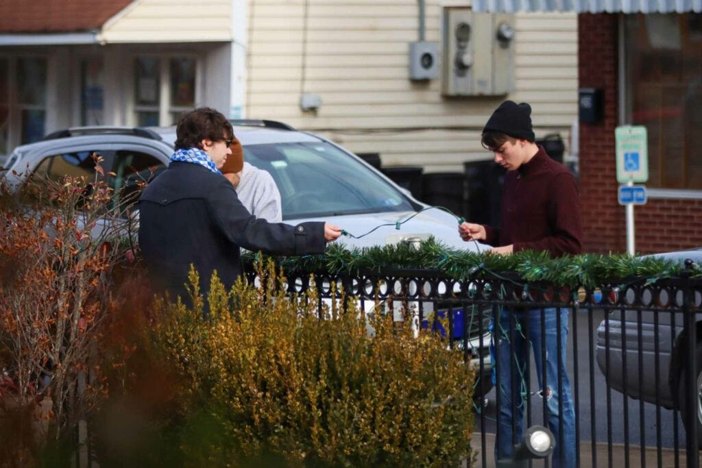 Glenville State College Student Government Association officers Garrett Watts (left) and Cody Dye add lights to the decorations at Glenville’s City Square Park.