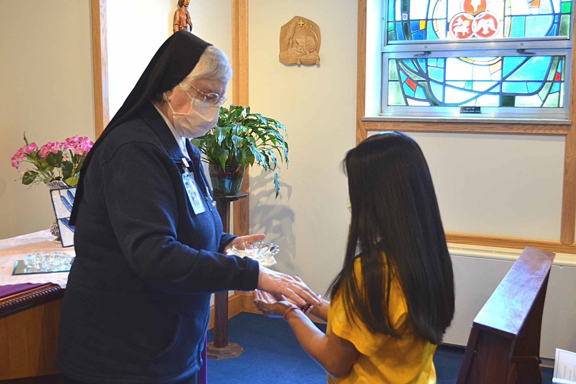 Sister Francesca Lowis, SAC, offers a blessing of the hands Friday to Ariana Long, who will be traveling with the Hands and Hearts for Christ to Guatemala in 2022 on a mission trip.