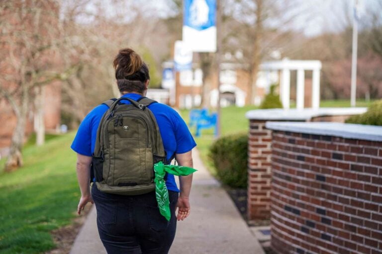 A student walking on the Glenville State University campus with a green bandana tied to their backpack. As part of the ongoing Green Bandana Initiative, Glenville State students are completing mental health training this spring. Once the training is complete, students will receive a green bandana that, when displayed on their backpacks or elsewhere, signals to other students that they are open to talking and are a source of support.