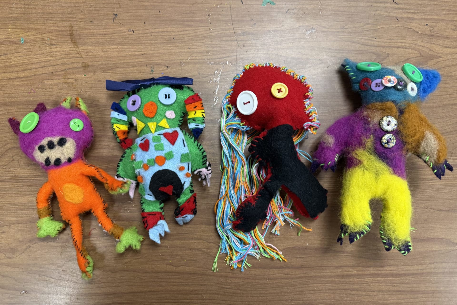 Four handmade plushie monsters created by B-UHS crafts students from first graders' original drawings