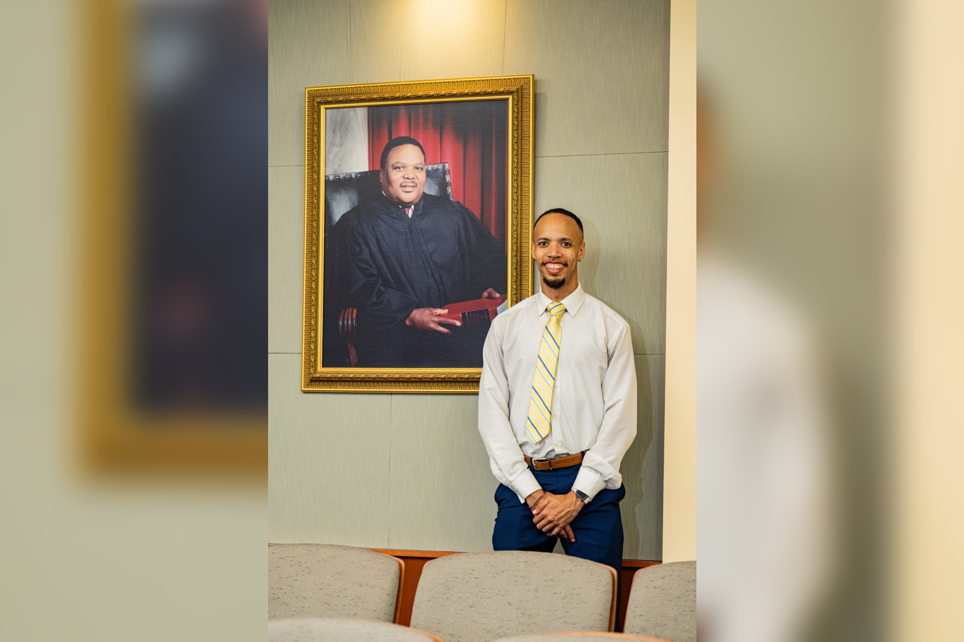 Chris Payne stands beside a portrait of his father, Wilbert A. Payne, inside the WVU College of Law, reflecting on the legacy he hopes to carry forward.
