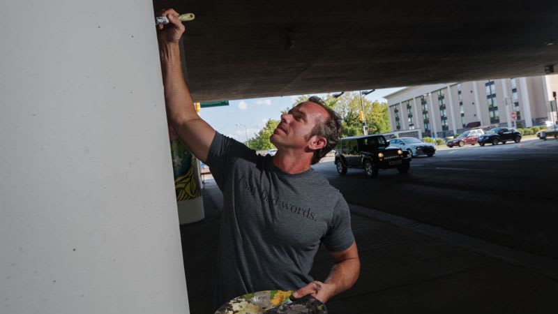 An artist paints a bridge pier.